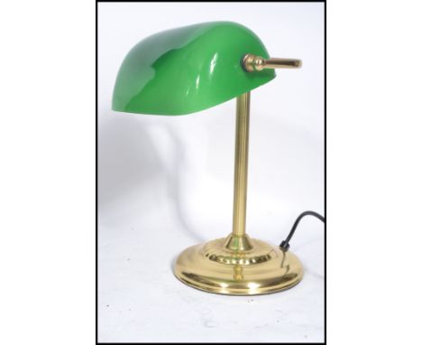 A vintage 20th century brass bankers lamp raised on a gilt circular base with adjustable green glass shade.