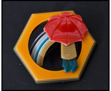 L&eacute;a Stein b1936: A vintage 20th century compressed plastic brooch in the form of a rainbow with girl and umbrella hous