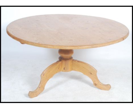 A 20th century country large pine dining table of circular form raised on a single pedestal base of tripod splayed legs.