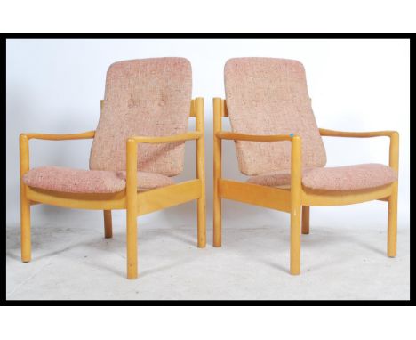 A pair of 20th century Ercol staff chairs. Light beech wood turned construction with shaped elbow rests having upholstered se