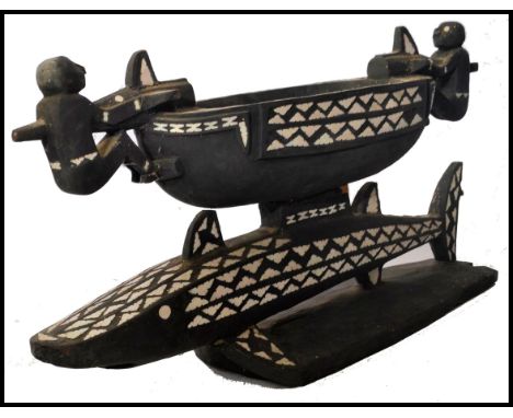 A vintage 20th century carved from an ebonised wood ceremonial Apira shell inlay tribal food bowl, the bowl raised on carved 