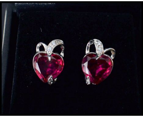 A pair of white gold and ruby and diamond earrings having heart shaped rubies. Complete in presentation box.