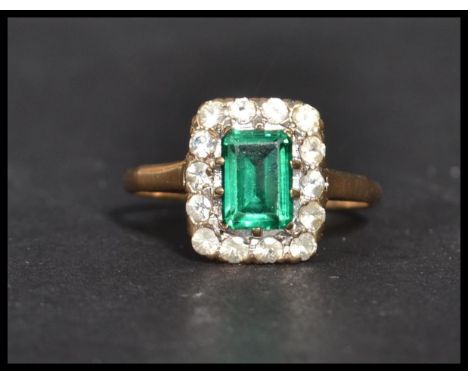 A vintage 20th century hallmarked 9ct gold green and white stone ring. The central emerald cut green stone adorned with a hal