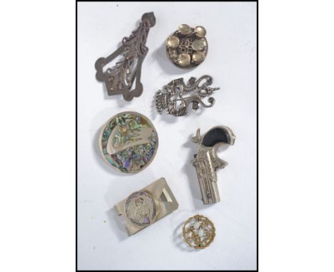 A group of vintage jewellery to include to include a silver white metal double dragon crown brooch a Victory miniature pistol