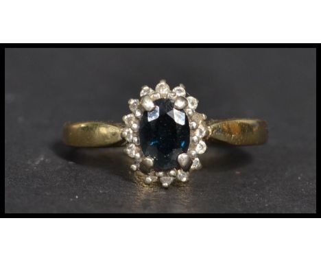 A vintage 20th century hallmarked 9ct gold diamond and sapphire ring. The central blue stone adorned with a halo of white sto