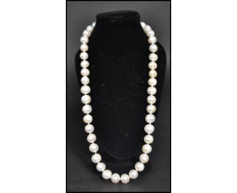 A vintage freshwater pearl necklace strand. The pearls of varying form but similar size. Claw clasp.  