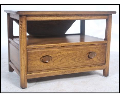 A 20th century Ercol ' Golden Dawn ' elm wood side table unit having a drop leaf table top with drawer to centre, all raised 