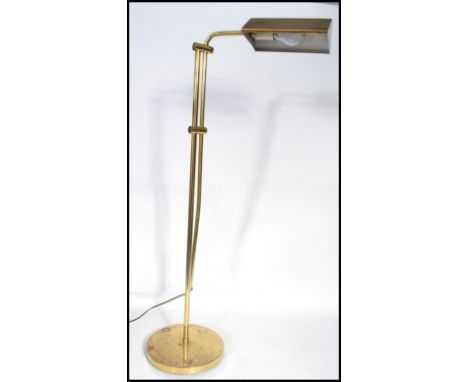 A vintage 20th century floor standing anglepoise brass bankers lamp having an adjustable shade raised on a circular base.