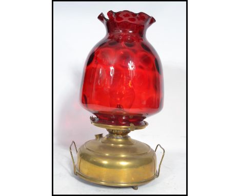 A vintage 19th century brass and cranberry glass oil lamp by Superba. The large flat brass reservoir base complete with flue 