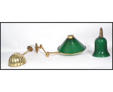 A group of three brass wall light fixtures to include two with green glass shades and another with a scallop shade. Longest m