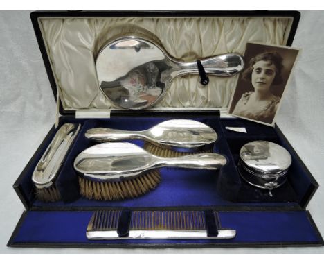 A cased six piece silver dressing table set of plain form including mirror, comb, three brushes &amp; lidded circular trinket