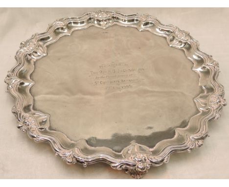 An Edwardian silver salver of circular form having raised pie crust rim with floral decoration, central inscription and trefo