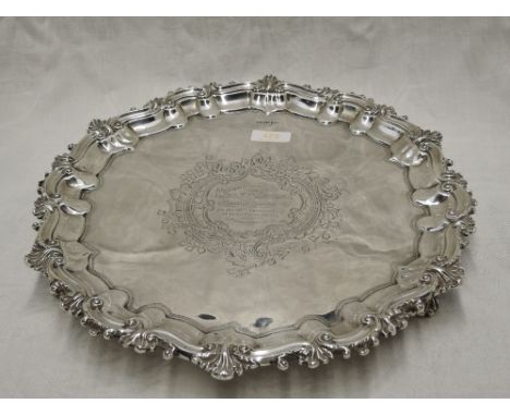 An Edwardian silver salver having moulded raised pie crust rim, trefoil bracket feet and central presentation inscription, Sh
