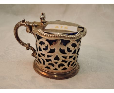 A Victorian silver lidded mustard pot having pierced decoration, moulded bow thumb rest and blue glass liner, Sheffield 1855,