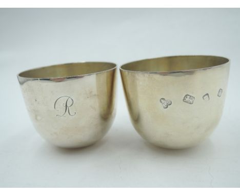 A pair of silver tumbler cups of plain form having curved weighted bases, initial J/R to side and over sized hallmarks, Londo