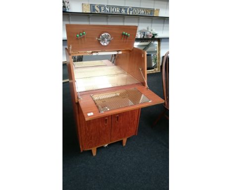 A small teak cocktail cabinet with mirrored interior and two doors below, to include a lemon squeezer and cherry spikes. (17)
