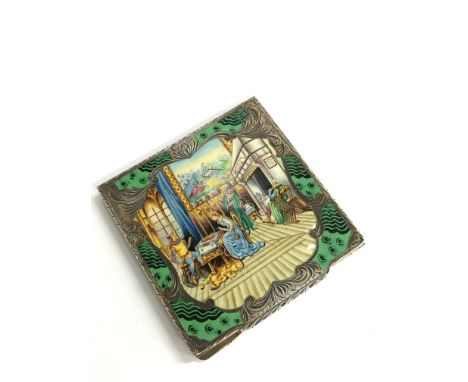 An 800 standard silver and enamelled powder compact depicting a Damsel in Distress at a Knight's Table, all over flat chased.