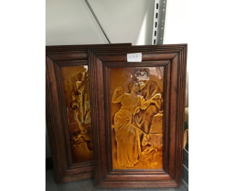 A pair of late 19th century oak framed Ault Pottery style brown glazed tiles decorated with young courting couples.