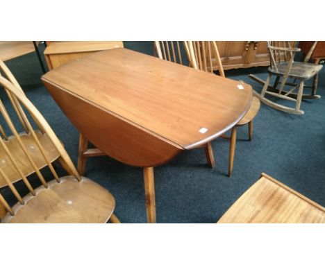 An Ercol drop-leaf dining table resting on cross stretcher support together with four matching stick-back dining chairs.