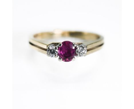 A 9ct yellow &amp; white gold three stone ring set with a central oval cut ruby, approx. 0.20 carats, set each side with a ro