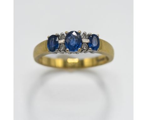 An 18ct yellow &amp; white gold ring set with three oval cut sapphires, total weight approx. 0.65 carats, interspaced by smal