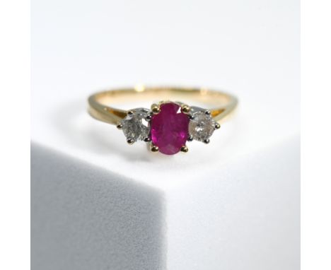 An 18ct yellow &amp; white gold three stone ring set with a central oval cut ruby, approx. 0.37 carats, set with a round bril