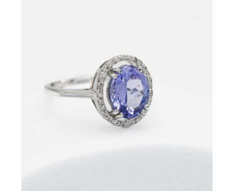 A 14ct white gold ring set with a central 2.63 carat AAA oval cut tanzanite, surrounded by small round cut diamonds, total we