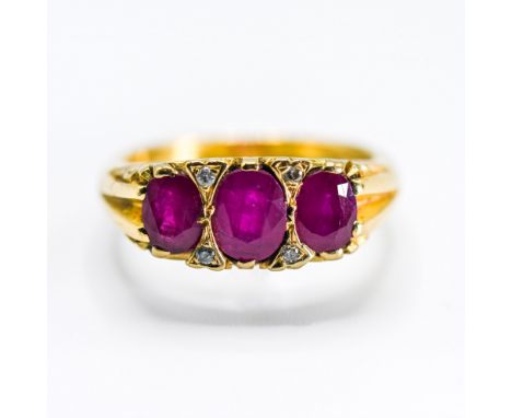 An 18ct yellow gold scroll design ring set with three oval cut rubies, total ruby weight approx. 1.35 carats, interspaced by 