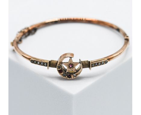 An antique 9ct rose gold bangle with a central moon &amp; star design set with seed pearls, three old small rough cut diamond