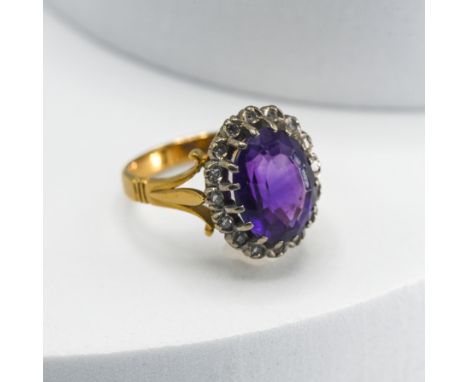 An 18ct yellow &amp; white gold cluster ring set with an oval cut amethyst surrounded by small single cut diamonds, 7.80gm, s