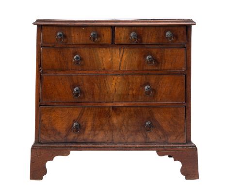A George III miniature walnut chest of drawers, circa 1770; the top with moulded edges above two short and three graduated lo