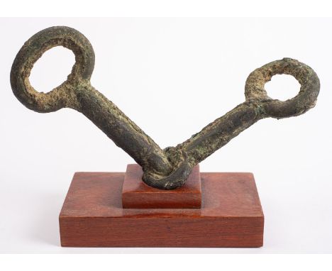 A Chinese bronze horse snaffle bit probably Tang Dynasty, 19cm hardwood stand.