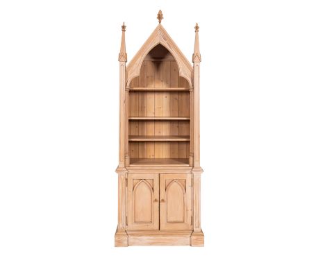 A pine cabinet bookcase in 'Gothic' taste, modern; the panelled gable and cusped arch with crocketed finials above open shelv