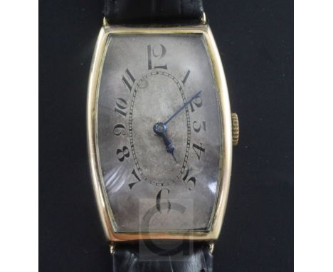 A gentleman's 1920's 9ct gold Regnia manual wind wrist watch, with tonneau case and silvered Arabic dial, on later associated