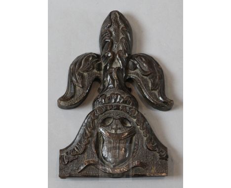 A 16th century carved oak pew end finial, carved with a fleur de lys above an armorial, 10in.