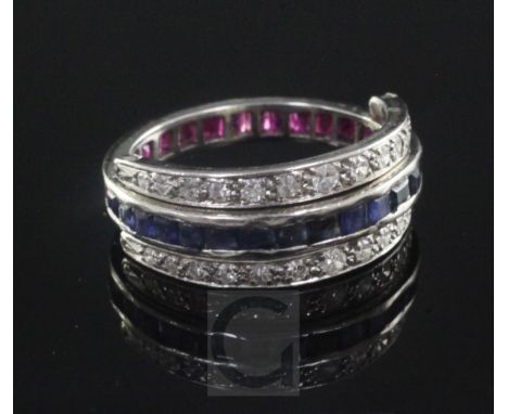 A mid 20th century platinum, sapphire, ruby and diamond triple band swivel ring, size M.