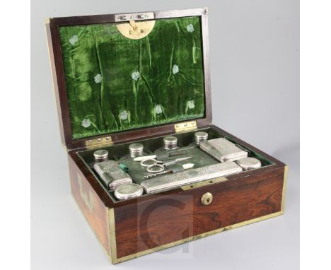 A George IV brass mounted rosewood travelling toilet box, fitted with nine silver mounted glass jars and three tools, with la