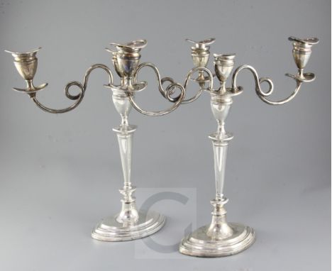 A pair of George V silver two branch, three light oval candelabra by Barker Brothers, with scrolling arms and tapering stems,