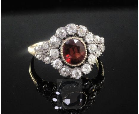 A late Victorian gold and silver, garnet and old cut diamond oval cluster ring, with ribbed shoulders, size R.