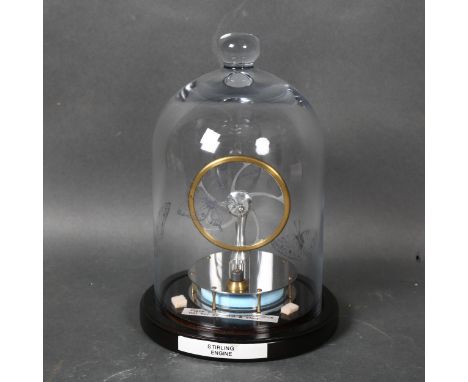 A Stirling engine, mounted under glass dome on stand, height 24cm overall. 