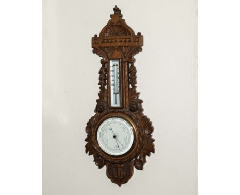 A carved oak barometer.