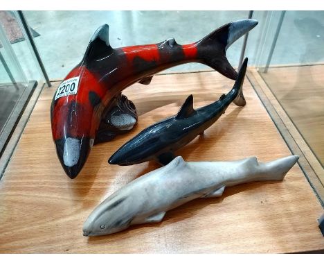 Two ceramic sharks and a stone shark 
