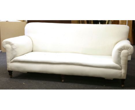 A large late Victorian Howard type sofa, the high back above stuff over seat and roll arms, upholstered in calico on square t