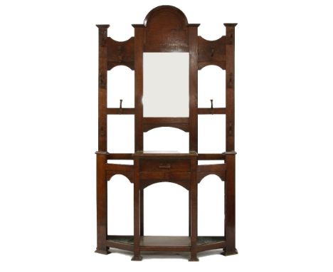 An oak Arts and Crafts mirror back stick stand, with shaped crest above bevelled plate, and central drawer, 133cm wide, 232cm