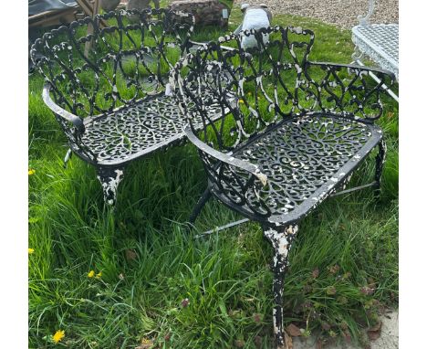 A pair of black painted (previously white) cast iron garden two seat bench seats, the shallow curved backs with scrollwork de