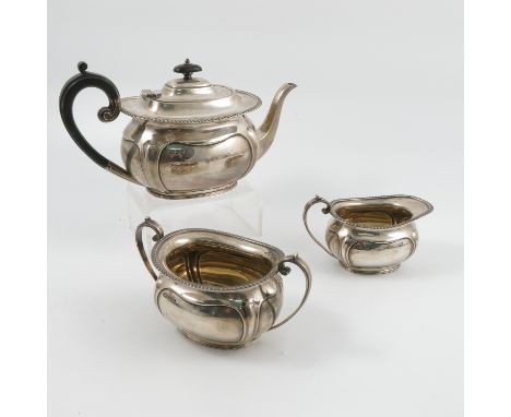 A silver three piece tea set, with gadrooned edge and shaped panels to the body, Sheffield 1909, maker Harrison Brother & How