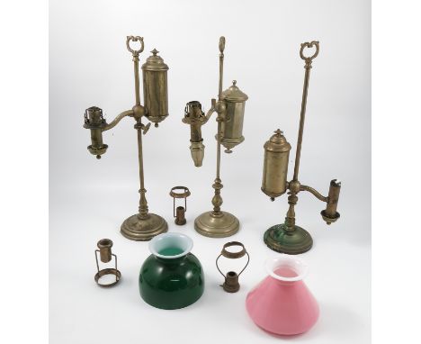Two Smethurst brass student lamps, with oil reserve, together with another similar lamp and various brass fittings and two gl
