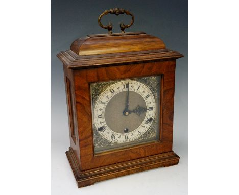 A walnut bracket clock in George II style the domed top with brass carrying handle the face with silvered chapter ring, Roman