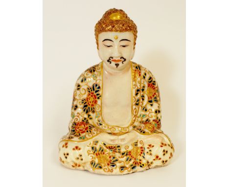 A Japanese stoneware mustached Buddha seated in the lotus position his hands in his lap, wearing a floral decorated cloak in 
