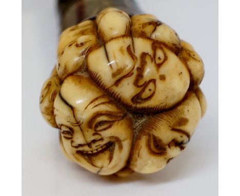 A Japanese walking stick, the ivory terminal carved with a multitude of Noh masks or a 'Thousand Faces' bearing various expre